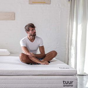 Man sitting on the Tuur® Topper which consists of 100% natural latex.